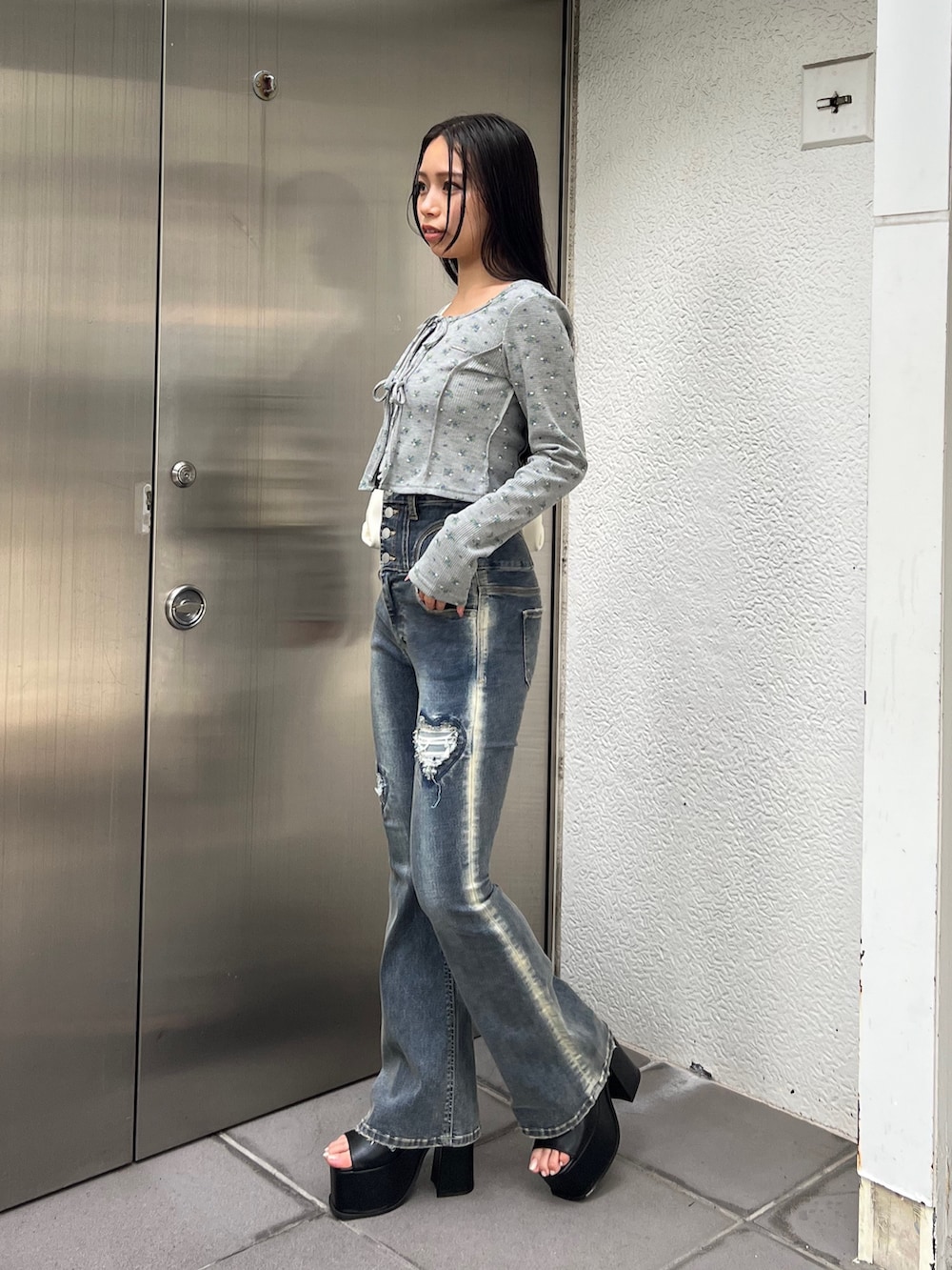 グレー系のTシャツ/カットソー、ブルー系のデニムパンツ、ホワイト系のハンドバッグを着用したレディースの夏コーディネートの2枚目の写真
