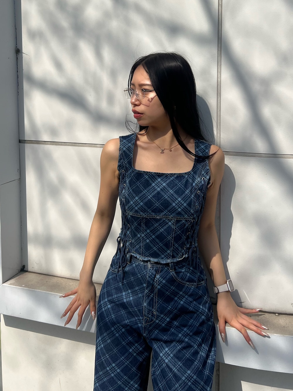 ブルー系のタンクトップ、ブルー系のデニムパンツ、ホワイト系のスニーカーを着用したレディースの春コーディネートの4枚目の写真