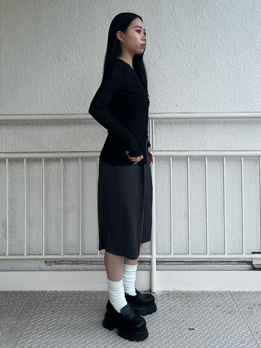 グレー系のその他パンツ、ブラック系のニット/セーター、ブラック系のローファーを着用したレディースの春コーディネートの2枚目の写真