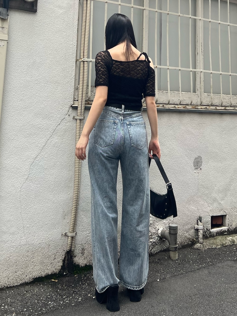 ブルー系のデニムパンツ、ブラック系のTシャツ/カットソー、ブラック系のハンドバッグを着用したレディースの夏コーディネートの3枚目の写真