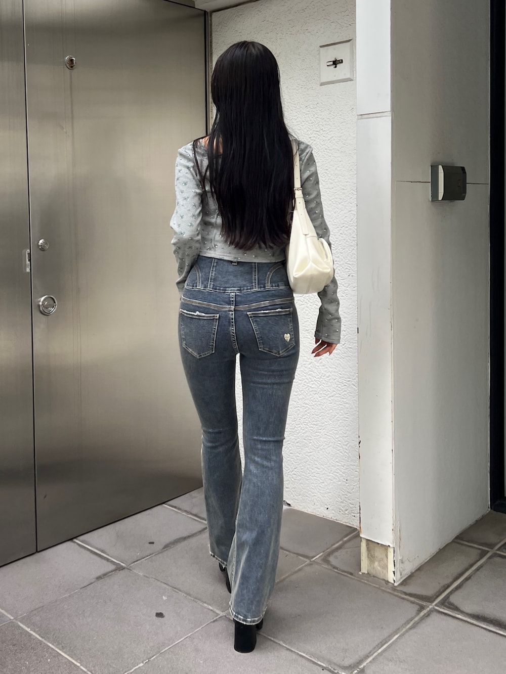 グレー系のTシャツ/カットソー、ブルー系のデニムパンツ、ホワイト系のハンドバッグを着用したレディースの夏コーディネートの3枚目の写真