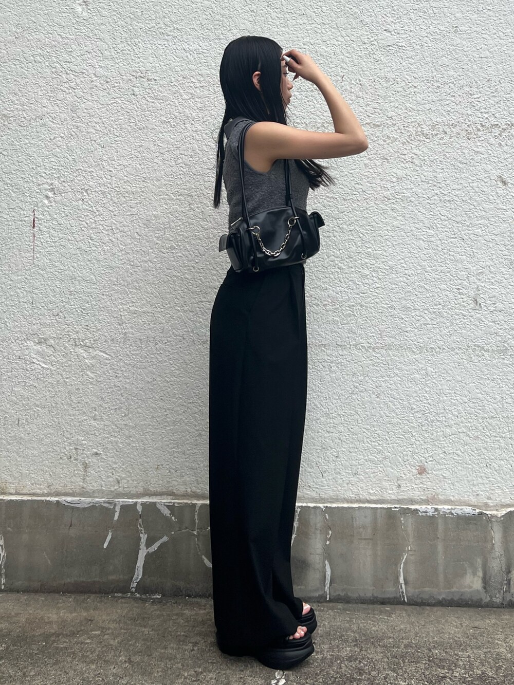 グレー系のニット/セーター、ブラック系のその他パンツ、ブラック系のハンドバッグを着用したレディースの夏コーディネートの2枚目の写真