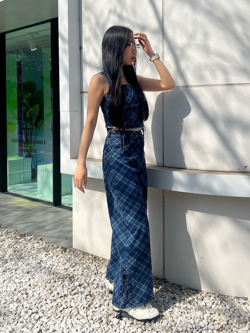 ブルー系のタンクトップ、ブルー系のデニムパンツ、ホワイト系のスニーカーを着用したレディースの春コーディネートの2枚目の写真