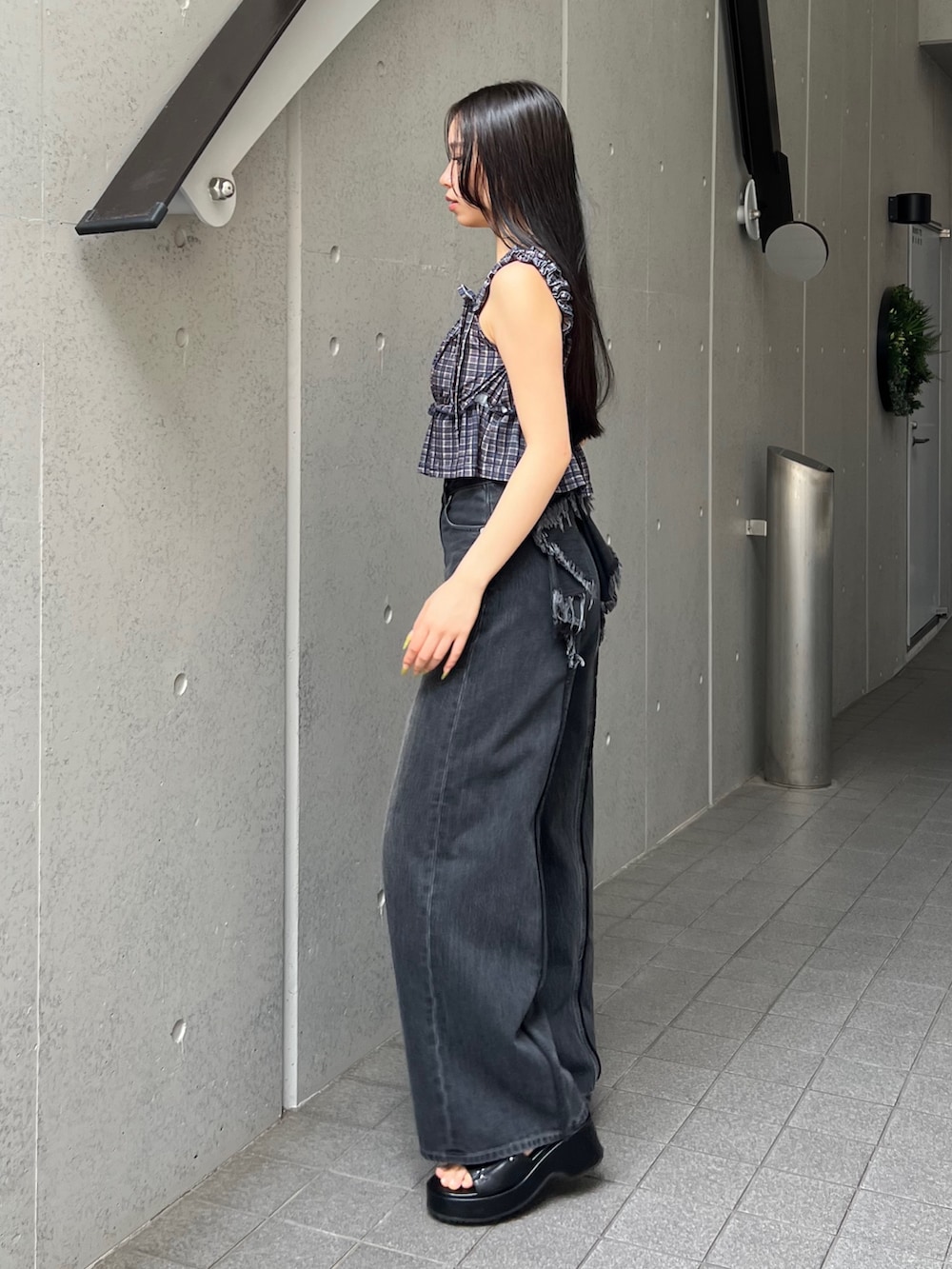 ブラウン系のタンクトップ、ブラック系のデニムパンツ、ブラック系のサンダルを着用したレディースの夏コーディネートの2枚目の写真