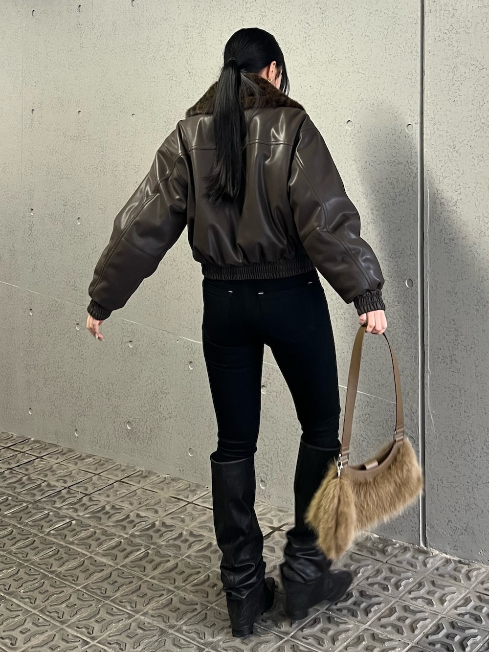 ブラウン系のブルゾン、ブラック系のデニムパンツ、ベージュ系のショルダーバッグを着用したレディースの冬コーディネートの3枚目の写真