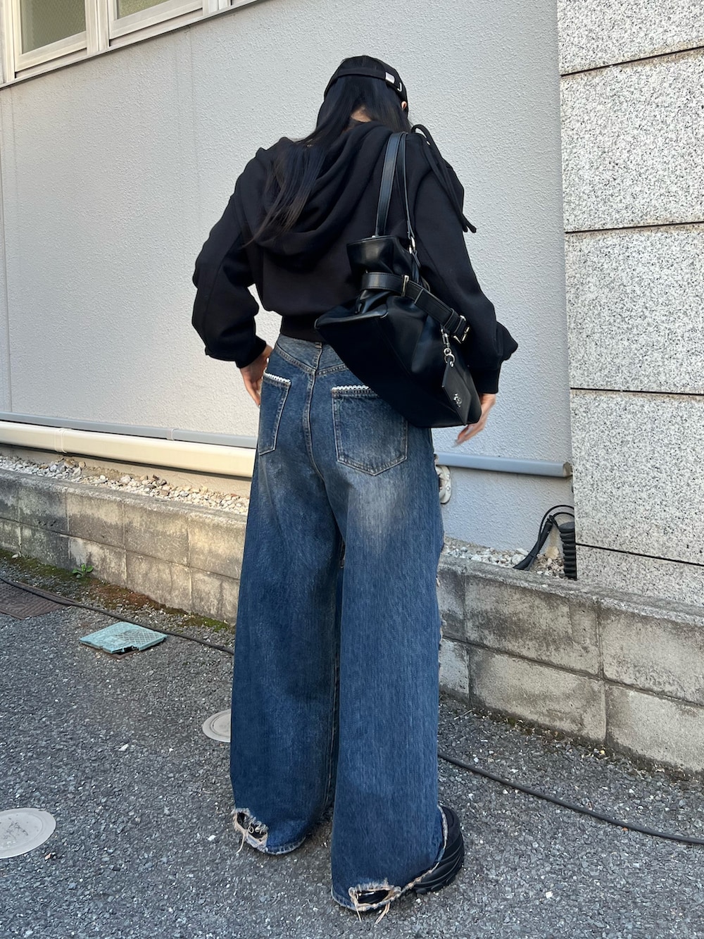 ブルー系のデニムパンツ、ブラック系のパーカー、ブラック系のスニーカーを着用したレディースの春コーディネートの3枚目の写真