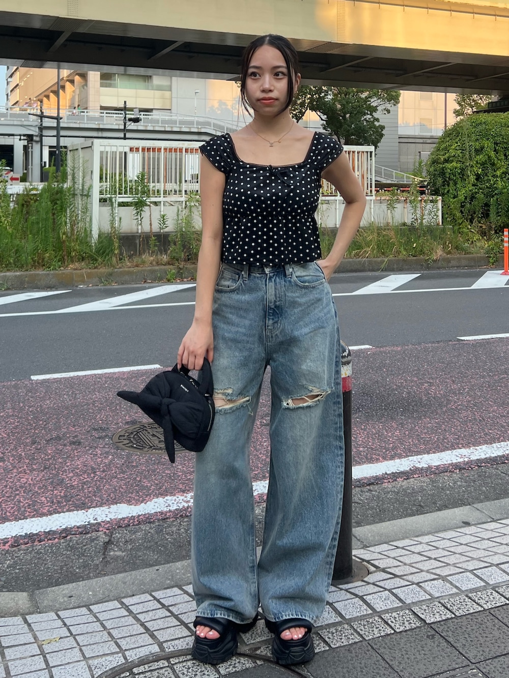 ブラック系のタンクトップ、ブルー系のデニムパンツ、ブラック系のハンドバッグを着用したレディースの夏コーディネートの2枚目の写真