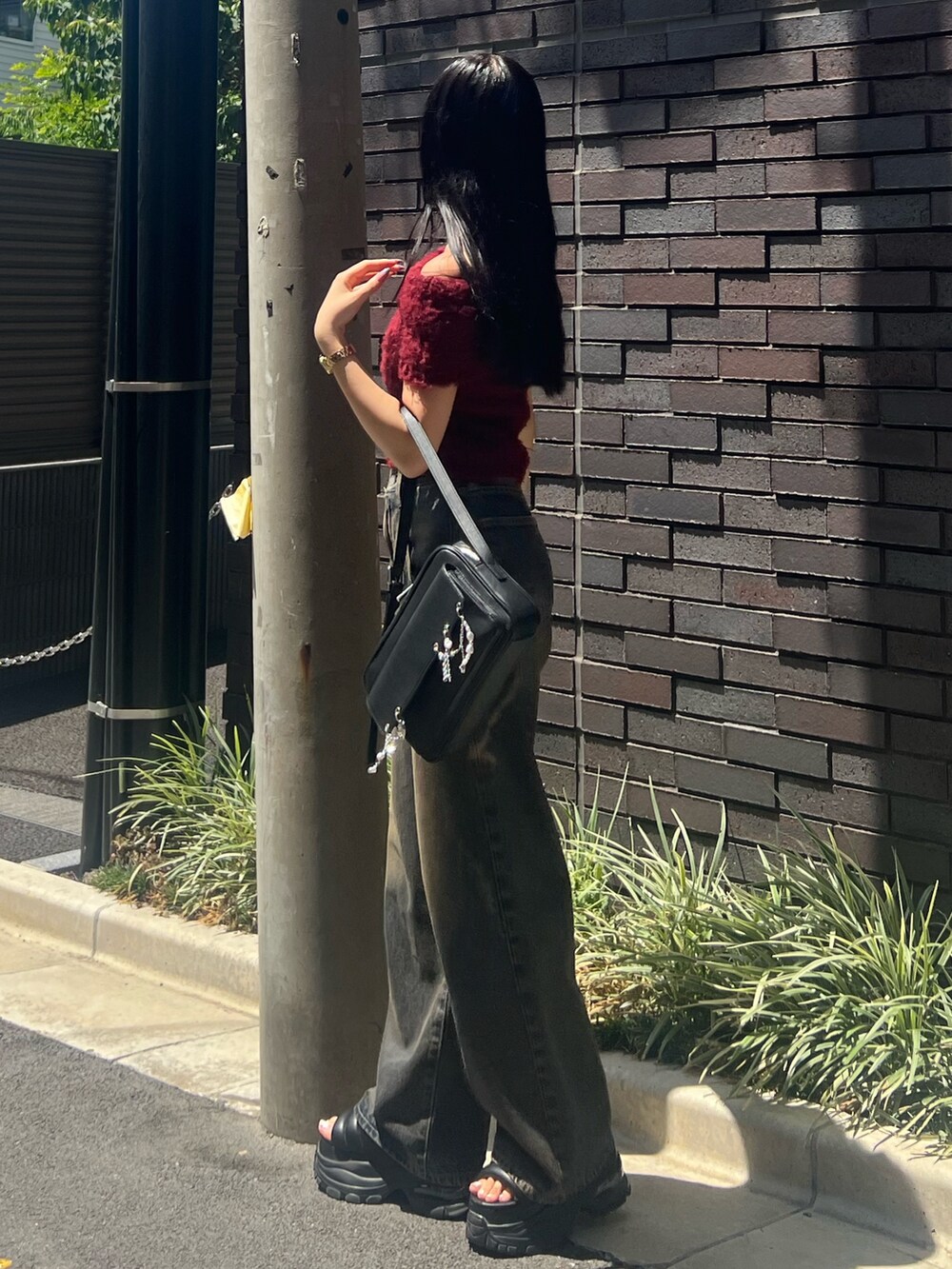 レッド系のニット/セーター、ブルー系のデニムパンツ、ブラック系のハンドバッグを着用したレディースの夏コーディネートの2枚目の写真