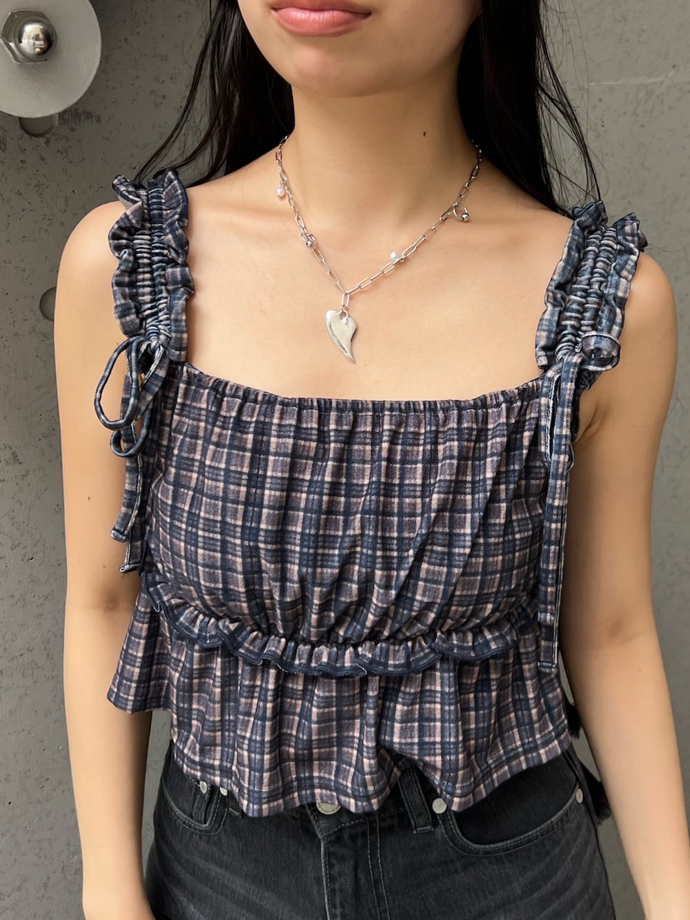 ブラウン系のタンクトップ、ブラック系のデニムパンツ、ブラック系のサンダルを着用したレディースの夏コーディネートの5枚目の写真