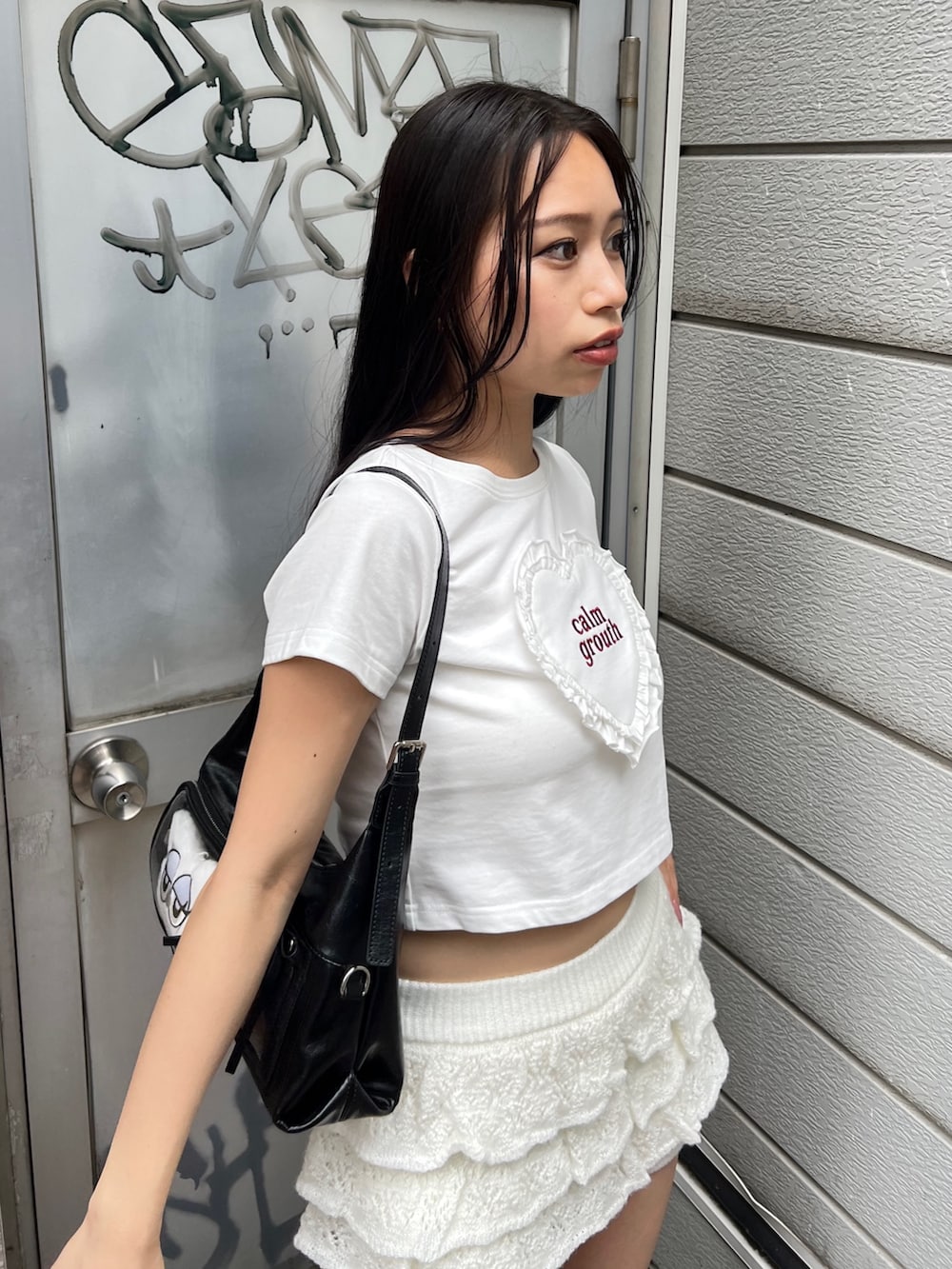 ホワイト系のTシャツ/カットソー、ホワイト系のスカート、ブラック系のハンドバッグを着用したレディースの秋コーディネートの4枚目の写真