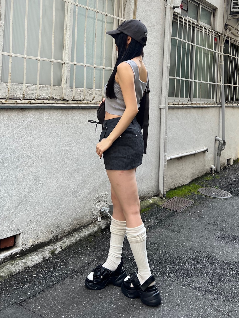 グレー系のスカート、ブラック系のハンドバッグ、ブラック系のサンダルを着用したレディースの夏コーディネートの2枚目の写真
