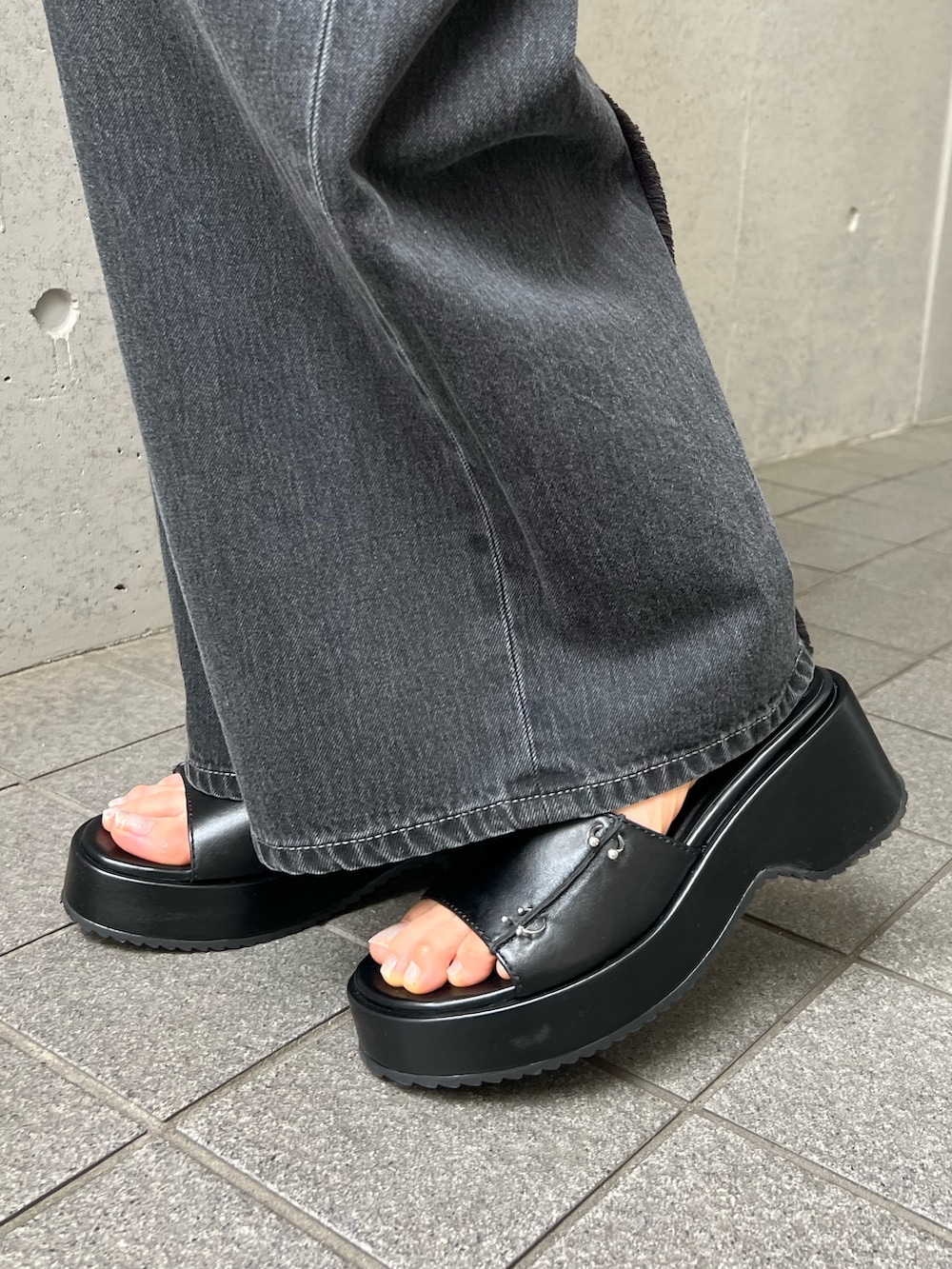 ブラウン系のタンクトップ、ブラック系のデニムパンツ、ブラック系のサンダルを着用したレディースの夏コーディネートの6枚目の写真