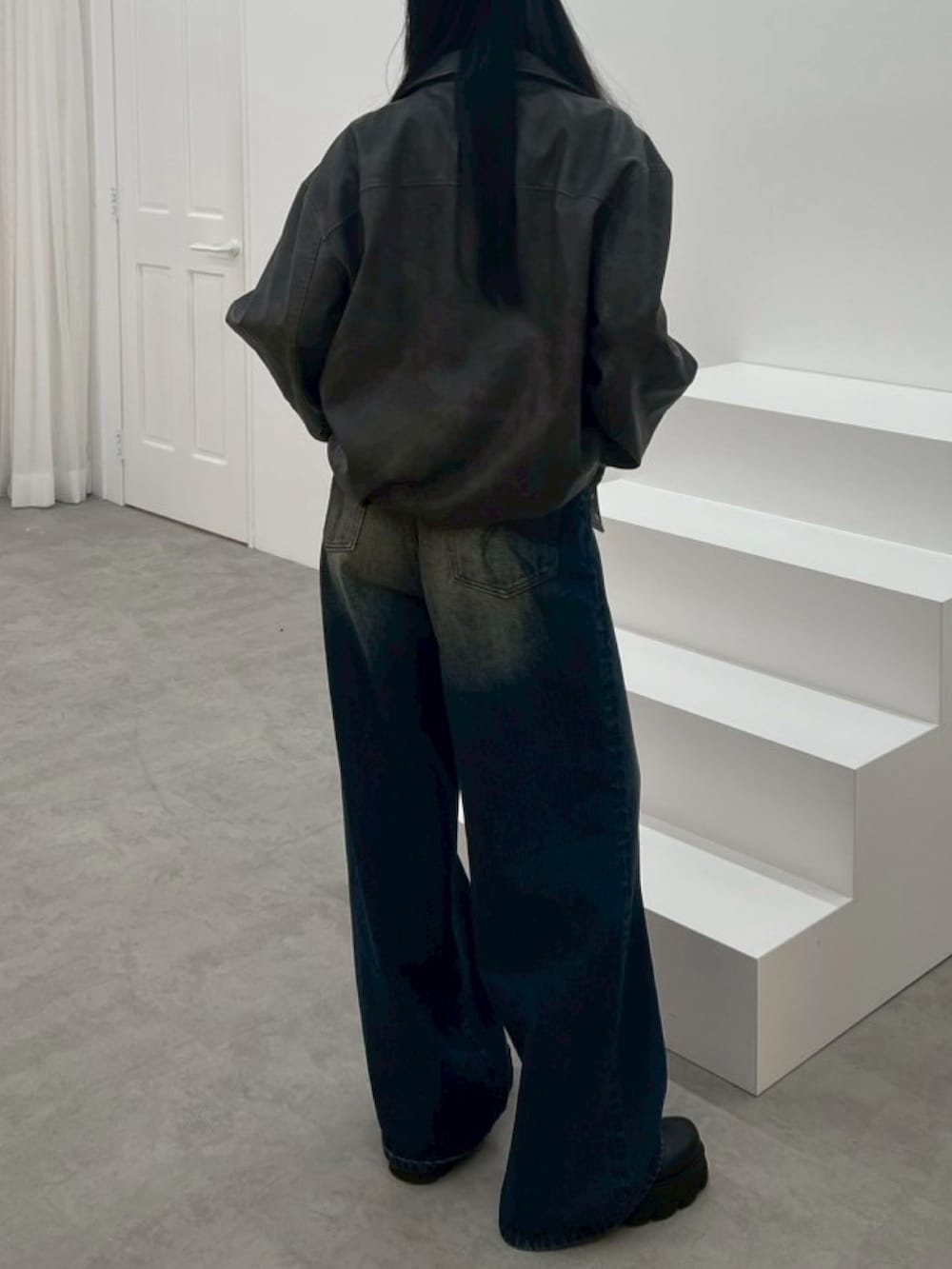 ブラック系のブルゾン、ホワイト系のニット/セーター、ブルー系のデニムパンツを着用したレディースの秋コーディネートの3枚目の写真