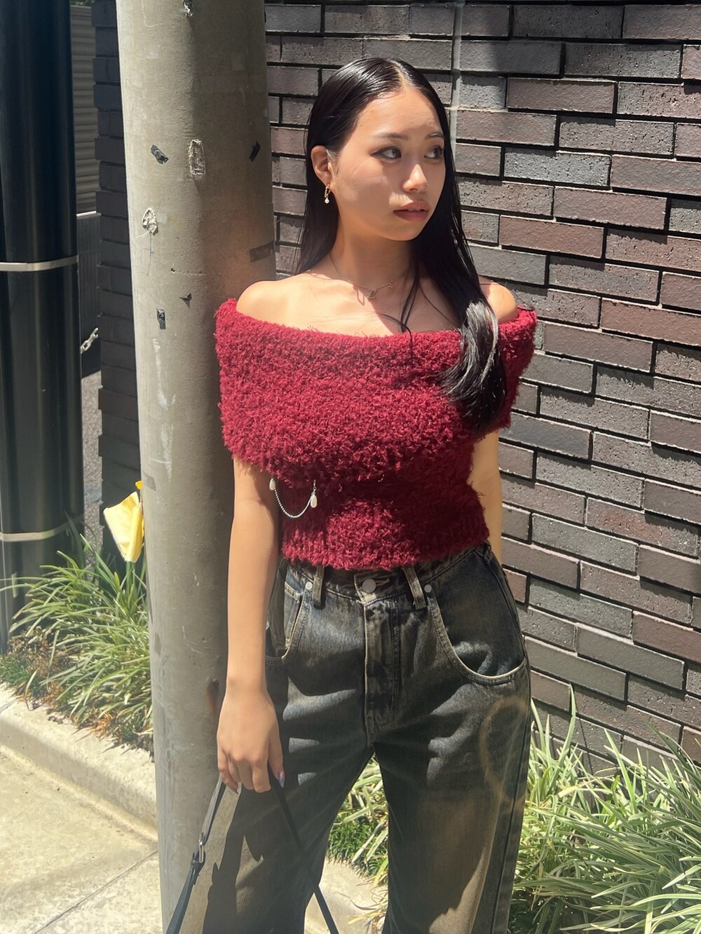 レッド系のニット/セーター、ブルー系のデニムパンツ、ブラック系のハンドバッグを着用したレディースの夏コーディネートの4枚目の写真