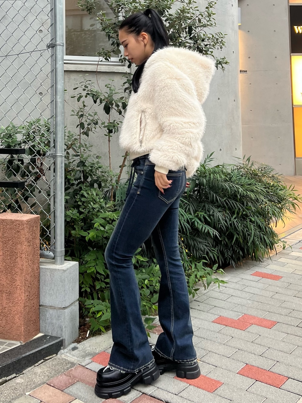 ホワイト系のブルゾン、ブルー系のデニムパンツ、ブラック系のローファーを着用したレディースの秋コーディネートの2枚目の写真