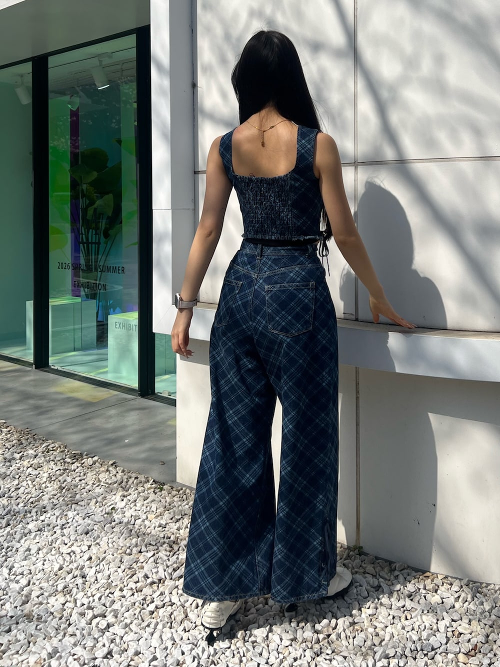 ブルー系のタンクトップ、ブルー系のデニムパンツ、ホワイト系のスニーカーを着用したレディースの春コーディネートの3枚目の写真