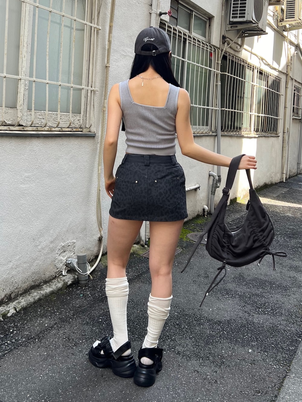 グレー系のスカート、ブラック系のハンドバッグ、ブラック系のサンダルを着用したレディースの夏コーディネートの3枚目の写真