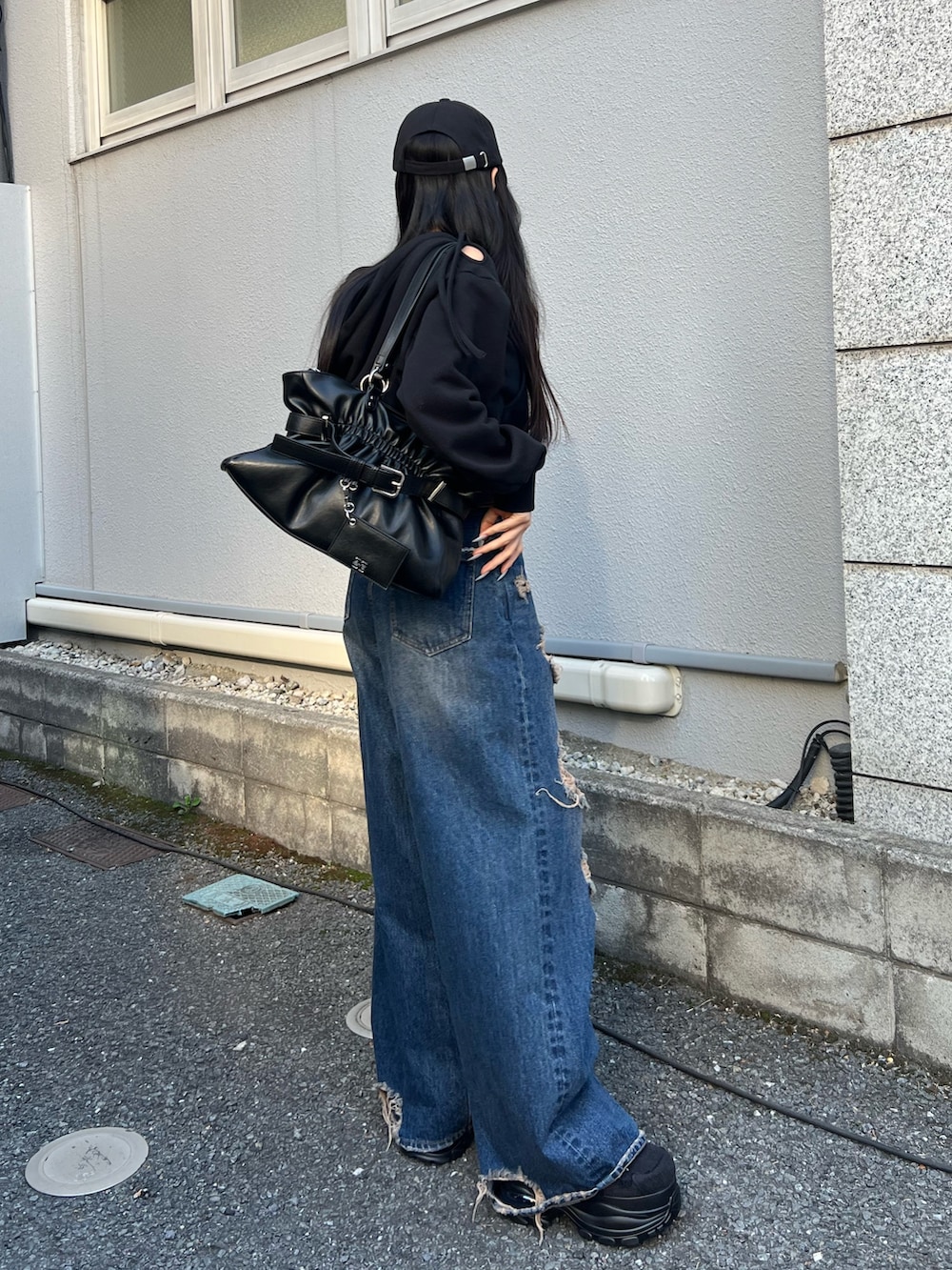 ブルー系のデニムパンツ、ブラック系のパーカー、ブラック系のスニーカーを着用したレディースの春コーディネートの2枚目の写真