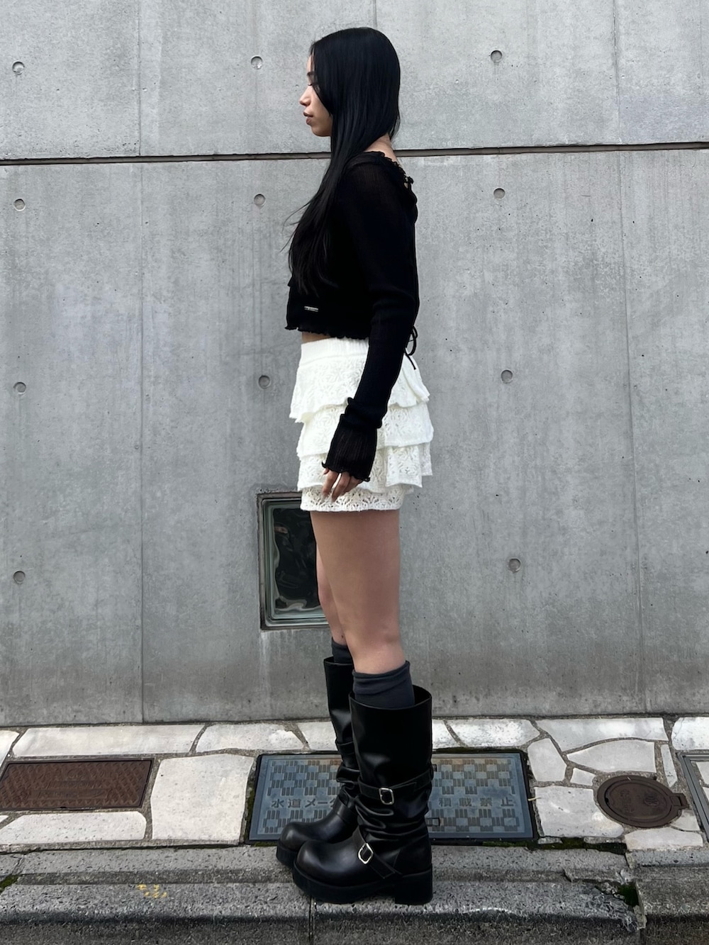 ブラック系のニット/セーター、ホワイト系のスカート、ブラック系のブーツを着用したレディースの冬コーディネートの2枚目の写真