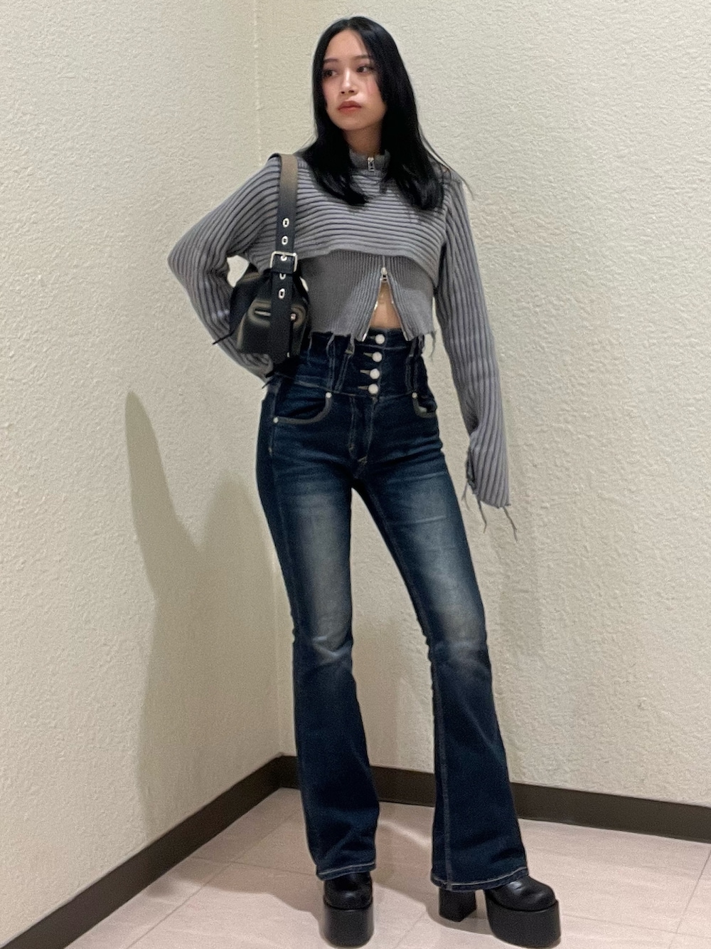 ブルー系のデニムパンツ、グレー系のニット/セーター、ブラック系のハンドバッグを着用したレディースの秋コーディネートの2枚目の写真