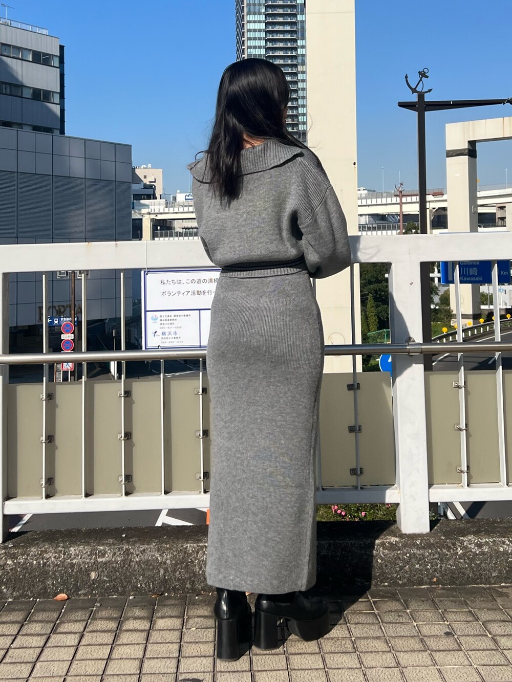 グレー系のスカート、グレー系のニット/セーター、ブラック系のブーツを着用したレディースの秋コーディネートの3枚目の写真