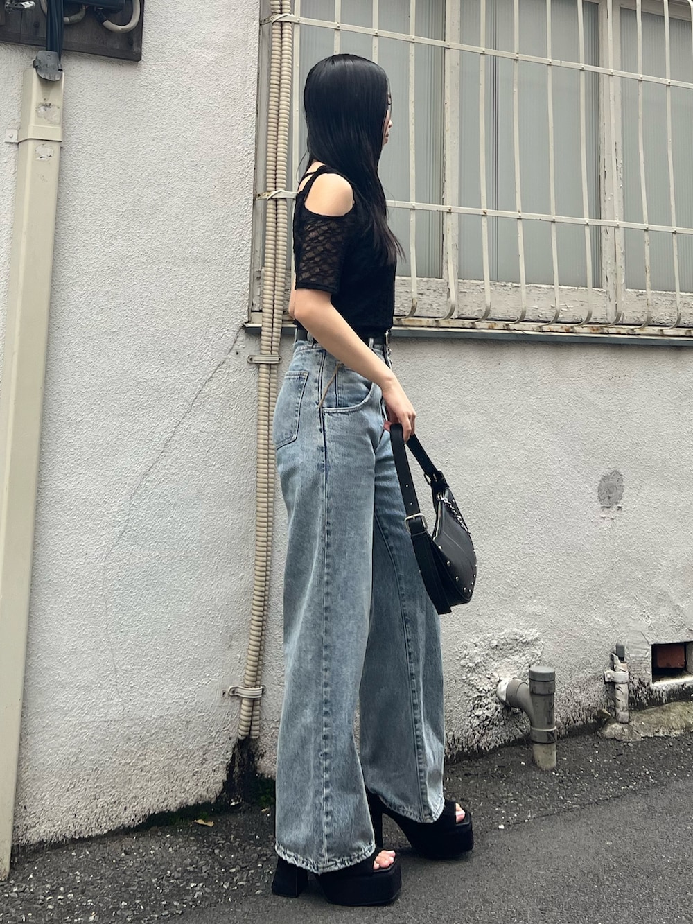ブルー系のデニムパンツ、ブラック系のTシャツ/カットソー、ブラック系のハンドバッグを着用したレディースの夏コーディネートの2枚目の写真