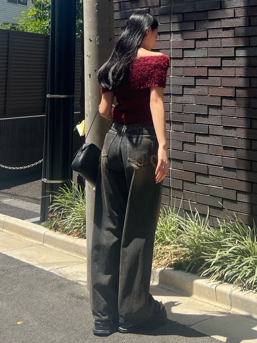 レッド系のニット/セーター、ブルー系のデニムパンツ、ブラック系のハンドバッグを着用したレディースの夏コーディネートの3枚目の写真