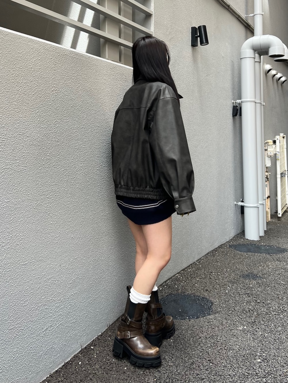 ブラック系のブルゾン、ブルー系のワンピース、ブラウン系のブーツを着用したレディースの秋コーディネートの2枚目の写真