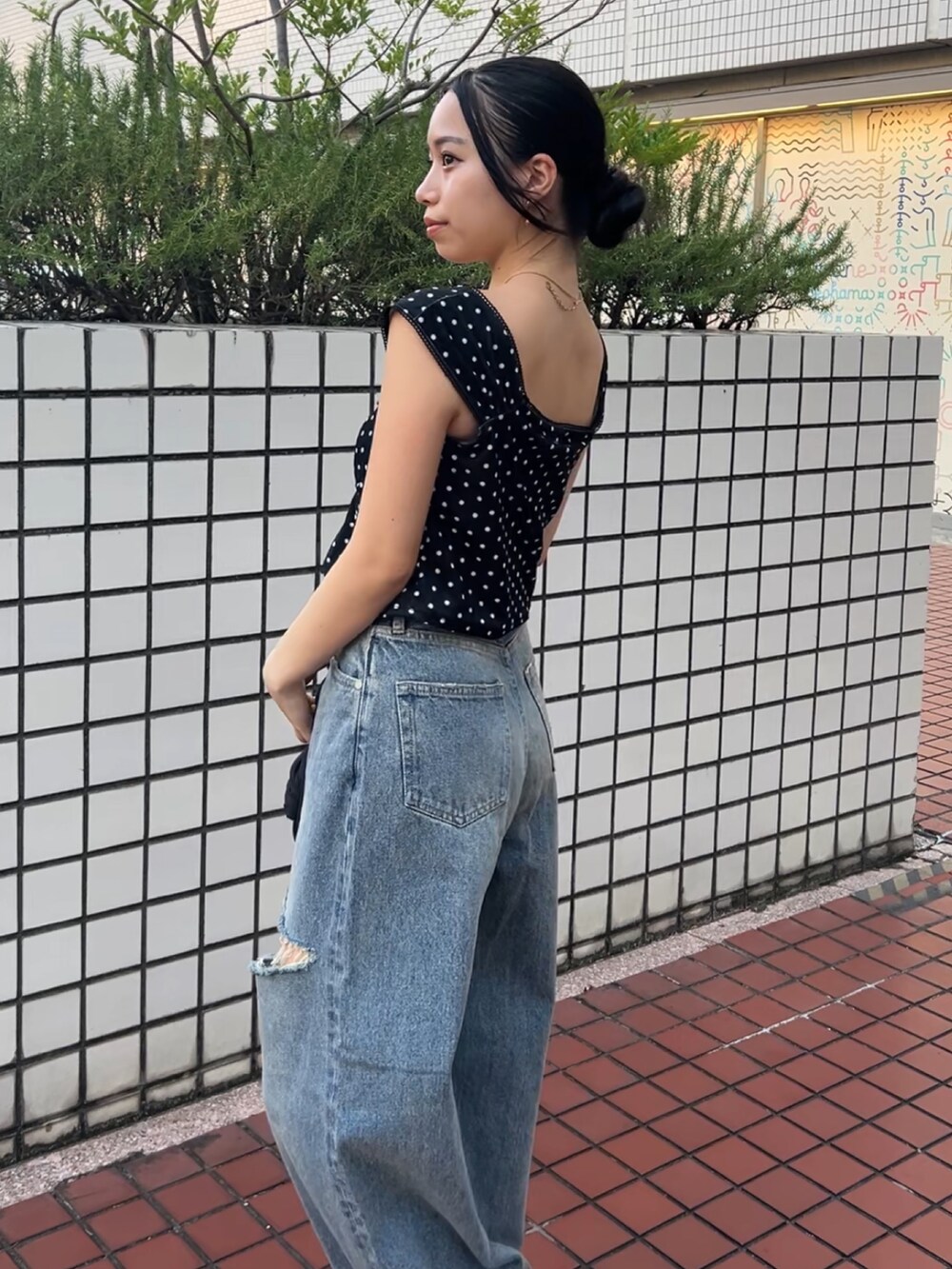 ブラック系のタンクトップ、ブルー系のデニムパンツ、ブラック系のハンドバッグを着用したレディースの夏コーディネートの3枚目の写真