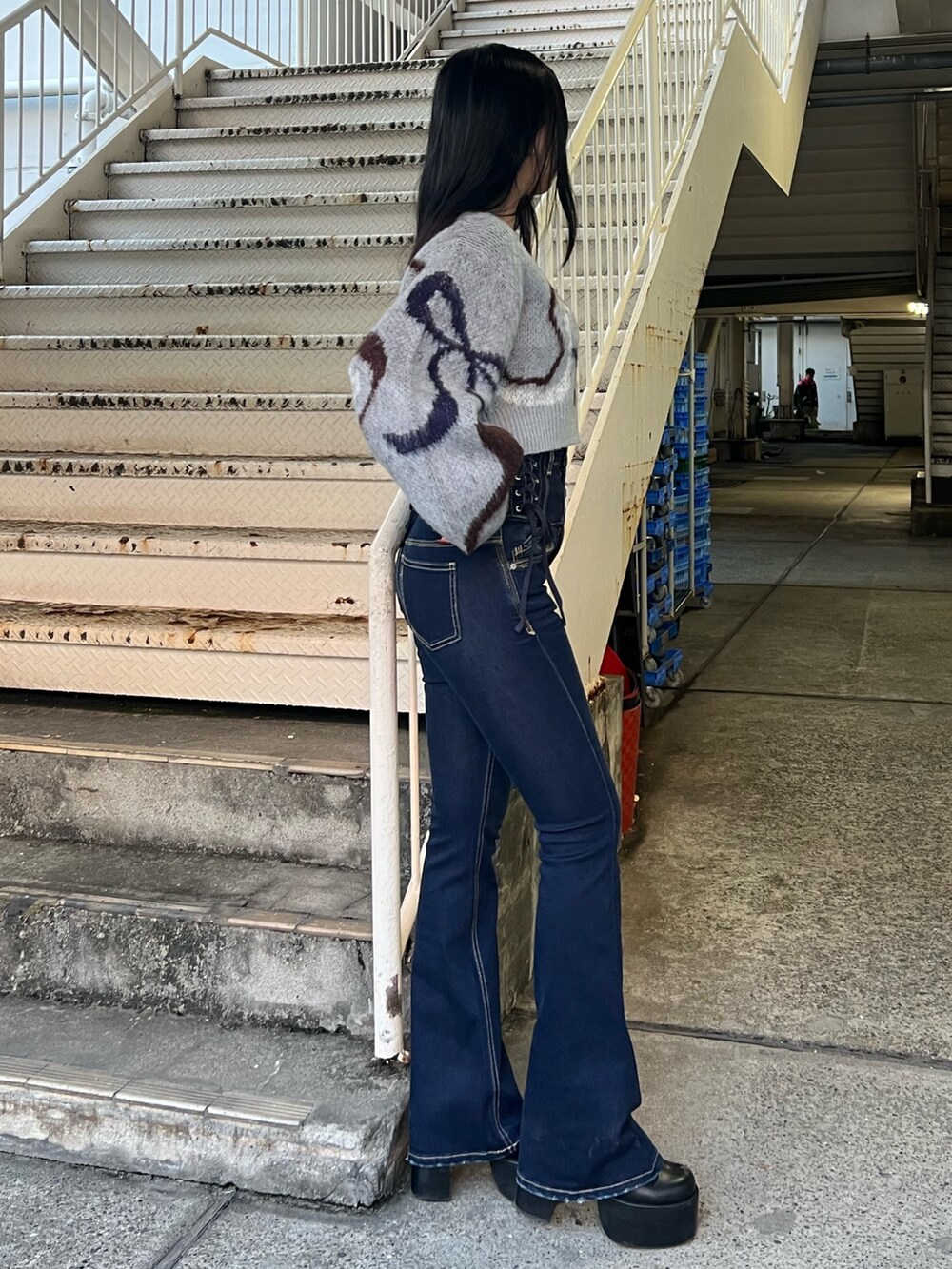 グレー系のニット/セーター、ブルー系のデニムパンツ、ブラック系のブーツを着用したレディースの秋コーディネートの2枚目の写真