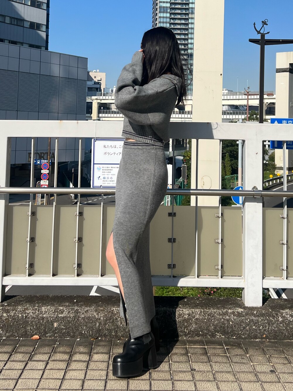 グレー系のスカート、グレー系のニット/セーター、ブラック系のブーツを着用したレディースの秋コーディネートの2枚目の写真