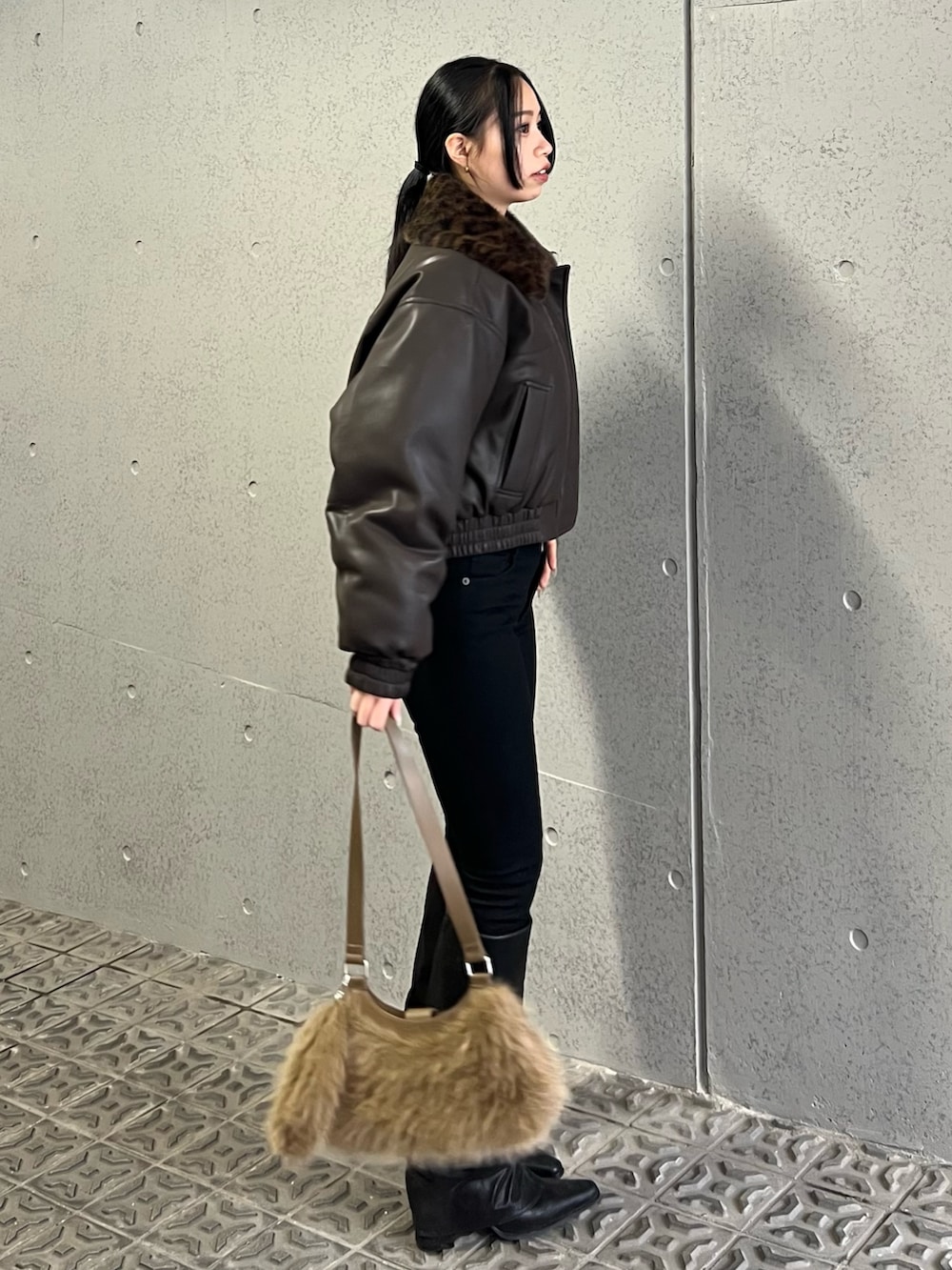 ブラウン系のブルゾン、ブラック系のデニムパンツ、ベージュ系のショルダーバッグを着用したレディースの冬コーディネートの2枚目の写真