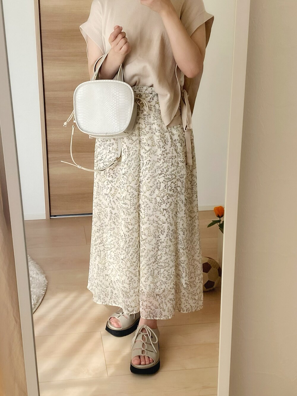 ホワイト系のショルダーバッグ、ホワイト系のタンクトップ、ベージュ系のベストを着用したレディースの夏コーディネートの3枚目の写真