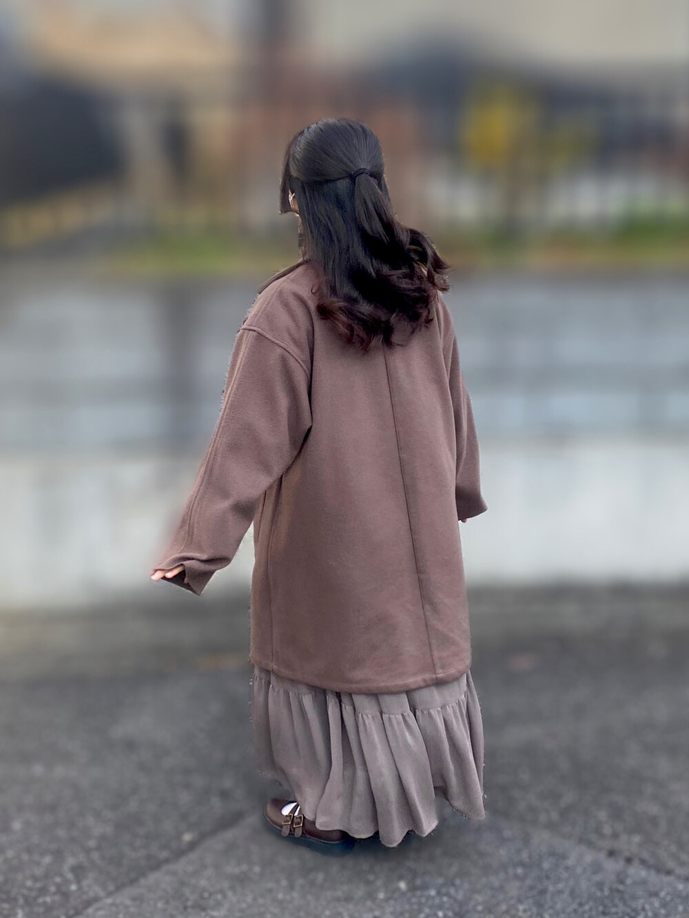 ブラウン系のトレンチコート、ベージュ系のブルゾン、ブラウン系のスカートを着用したレディースの冬コーディネートの2枚目の写真