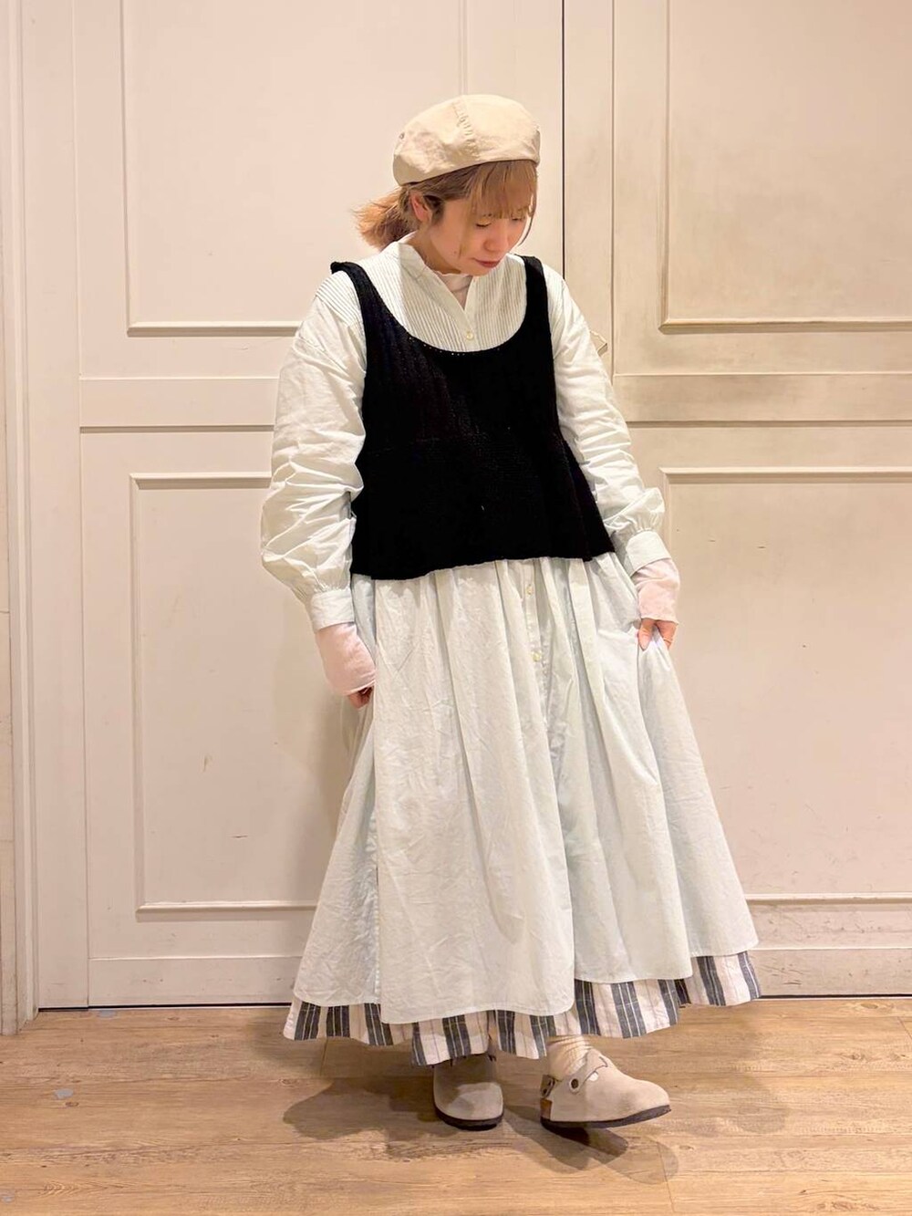 ブラック系のスカート、グリーン系のワンピース、ブラック系のベストを着用したレディースの春コーディネートの3枚目の写真