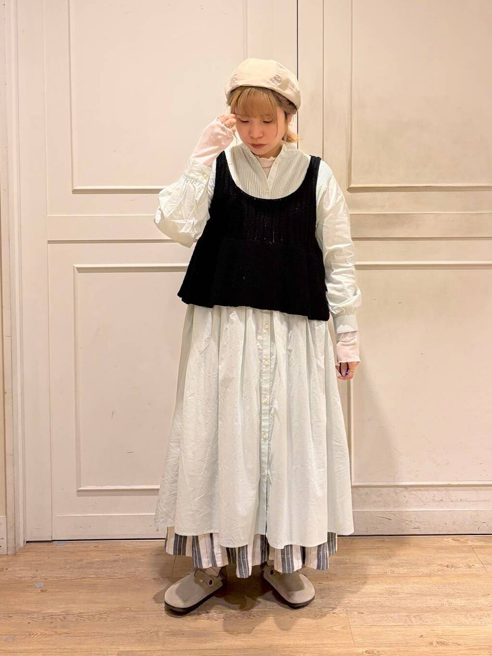 ブラック系のスカート、グリーン系のワンピース、ブラック系のベストを着用したレディースの春コーディネートの2枚目の写真