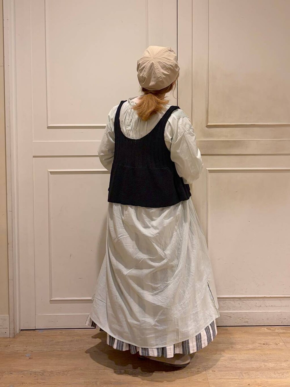 ブラック系のスカート、グリーン系のワンピース、ブラック系のベストを着用したレディースの春コーディネートの5枚目の写真