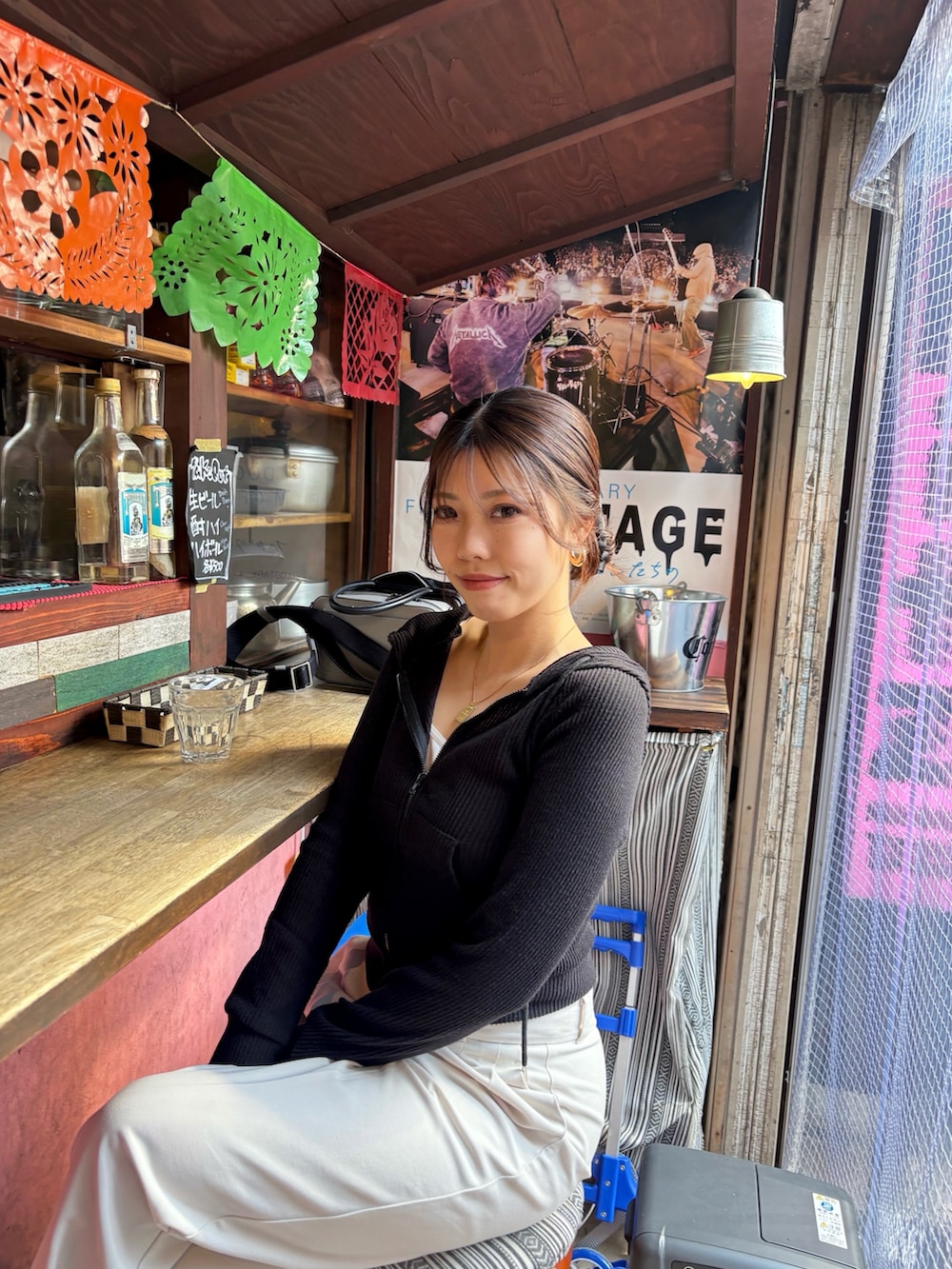 ホワイト系のスラックス、ブラック系のハンドバッグ、ブラック系のブーツを着用したレディースの春コーディネートの2枚目の写真