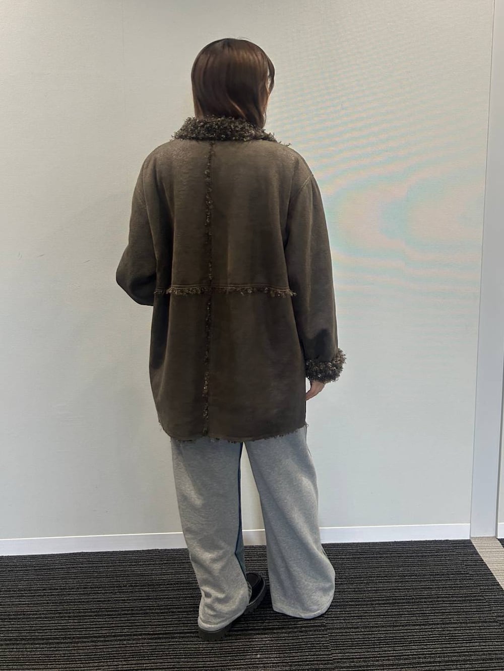 ブルー系のデニムパンツ、ブラウン系のムートンコート、ホワイト系のワンピースを着用したレディースの秋コーディネートの3枚目の写真