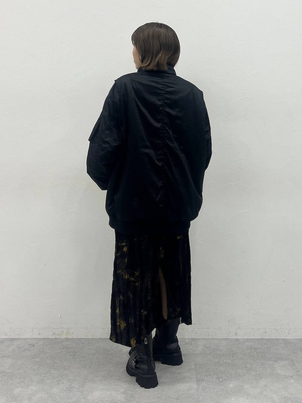 ブラック系のブーツ、ブラック系のブルゾン、パープル系のスカートを着用したレディースの秋コーディネートの3枚目の写真