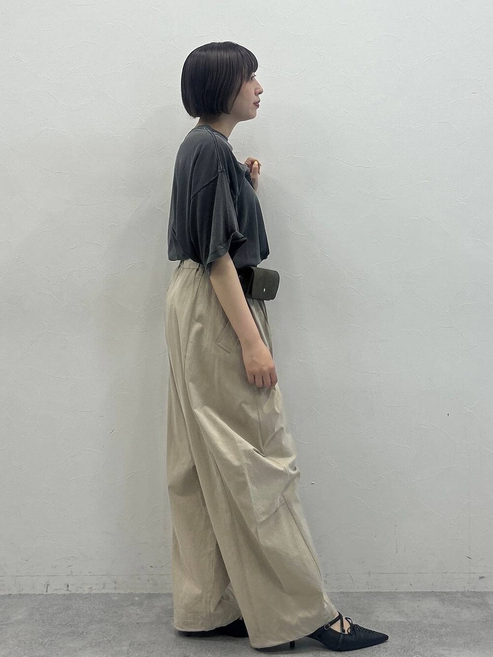 ベージュ系のその他パンツ、ブラック系のTシャツ/カットソー、グリーン系のポーチを着用したレディースの春コーディネートの3枚目の写真