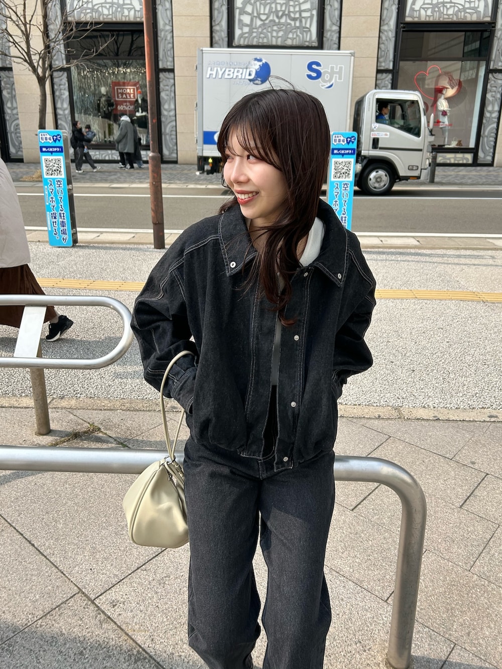 ホワイト系のショルダーバッグ、ブラック系のデニムパンツ、ブラック系のブルゾンを着用したレディースの冬コーディネートの3枚目の写真