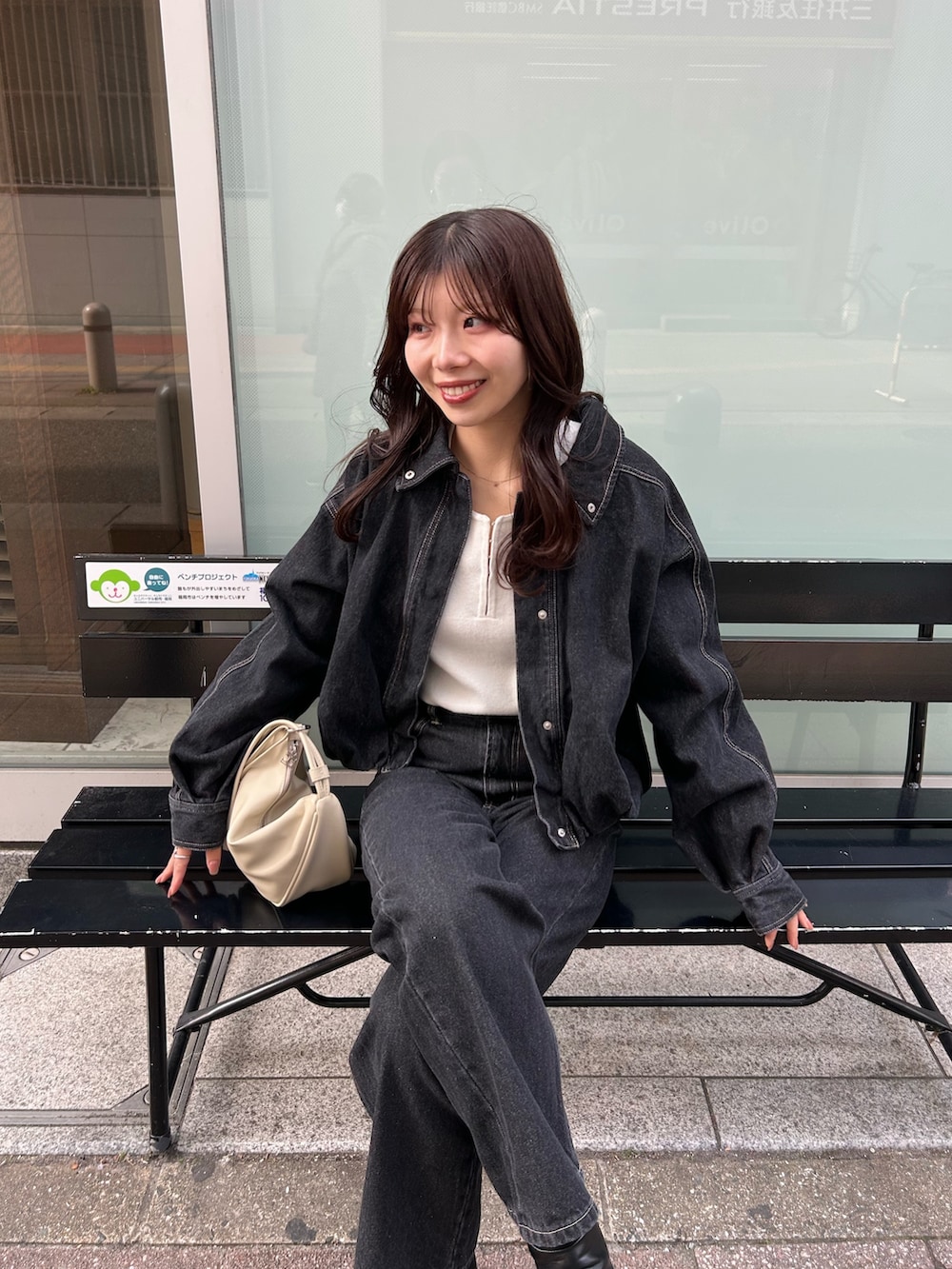 ホワイト系のショルダーバッグ、ブラック系のデニムパンツ、ブラック系のブルゾンを着用したレディースの冬コーディネートの4枚目の写真