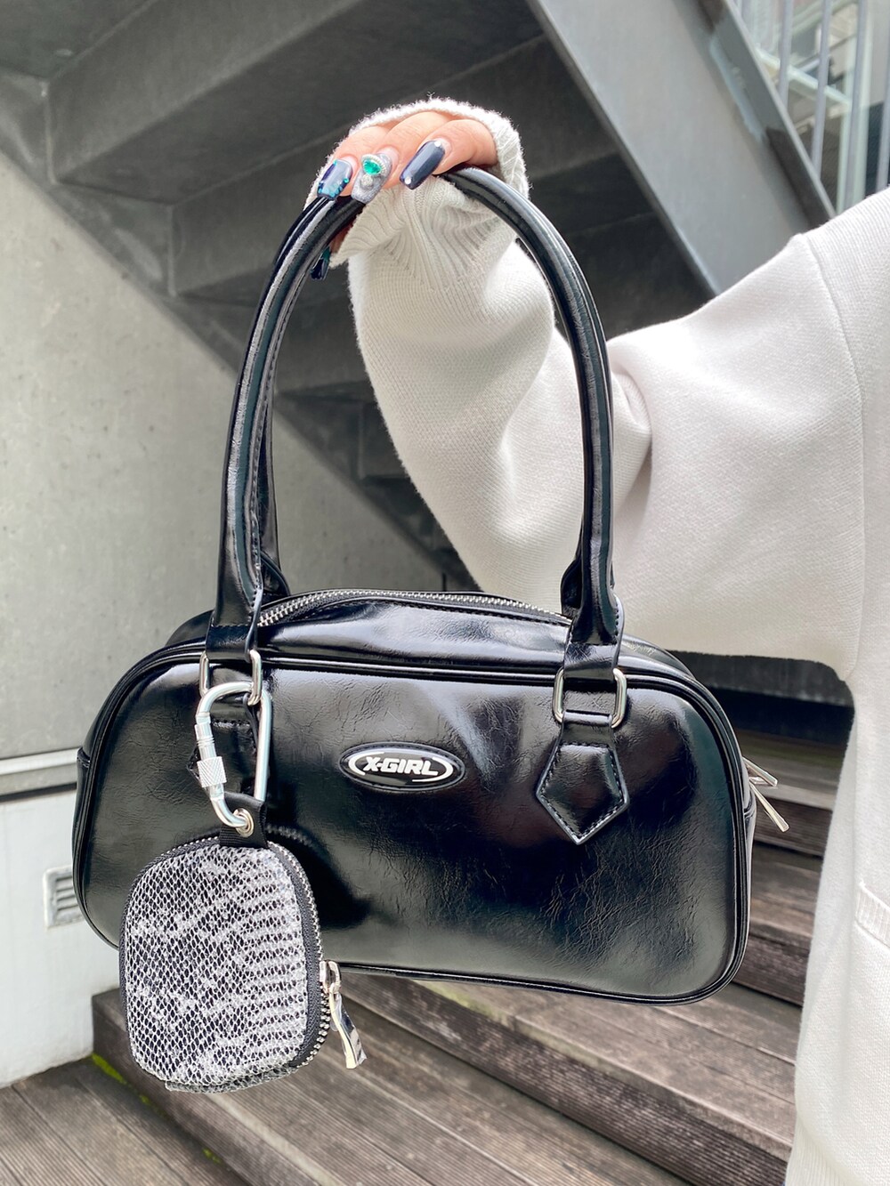 ブルー系のデニムパンツ、ホワイト系のカーディガン/ボレロ、ブラック系のハンドバッグを着用したレディースの秋コーディネートの3枚目の写真