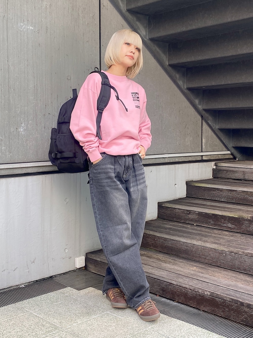 ピンク系のスウェット、ブラック系のデニムパンツ、ブラック系のバックパック/リュックを着用したレディースの冬コーディネートの2枚目の写真