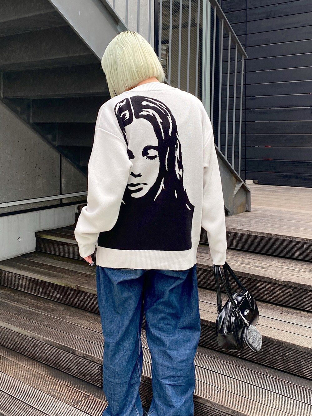 ブルー系のデニムパンツ、ホワイト系のカーディガン/ボレロ、ブラック系のハンドバッグを着用したレディースの秋コーディネートの4枚目の写真