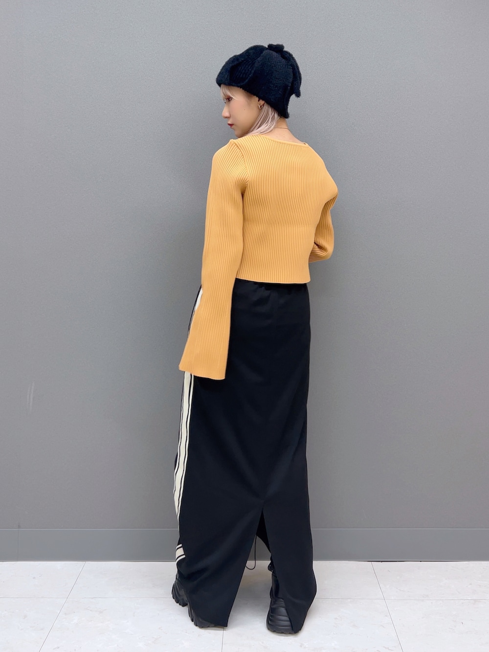 オレンジ系のカーディガン/ボレロ、ブラック系のスカート、ブラック系のブーツを着用したレディースの夏コーディネートの3枚目の写真