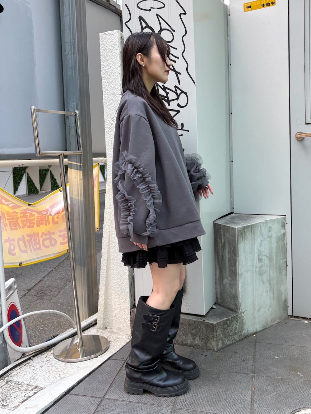 グレー系のTシャツ/カットソー、ブラック系のスカート、ブラック系のブーツを着用したレディースの冬コーディネートの2枚目の写真