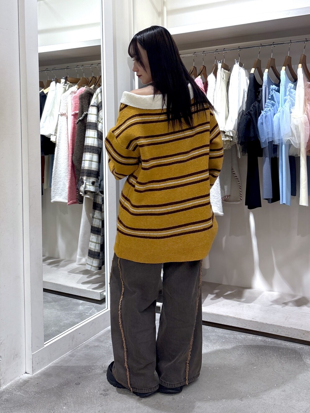 イエロー系のニット/セーター、ブラウン系のデニムパンツを着用したレディースの冬コーディネートの4枚目の写真