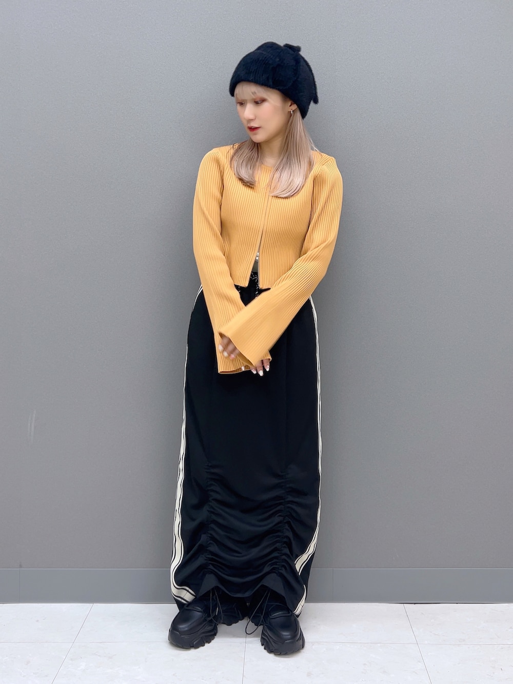 オレンジ系のカーディガン/ボレロ、ブラック系のスカート、ブラック系のブーツを着用したレディースの夏コーディネートの2枚目の写真